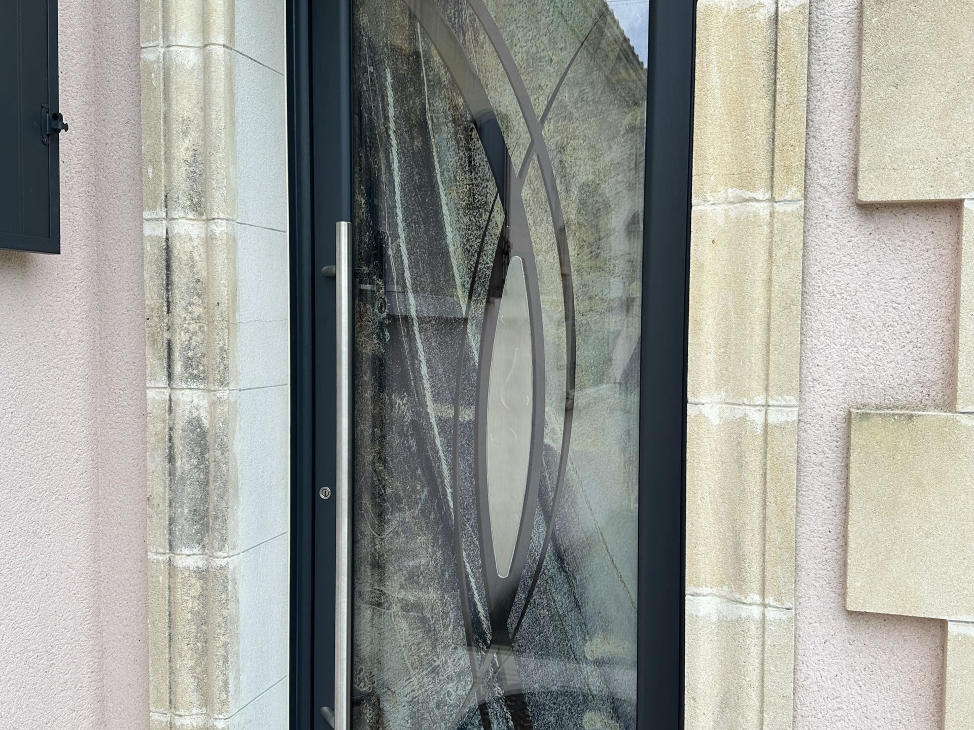 Porte moderne en verre et métal encadrée de pierre.