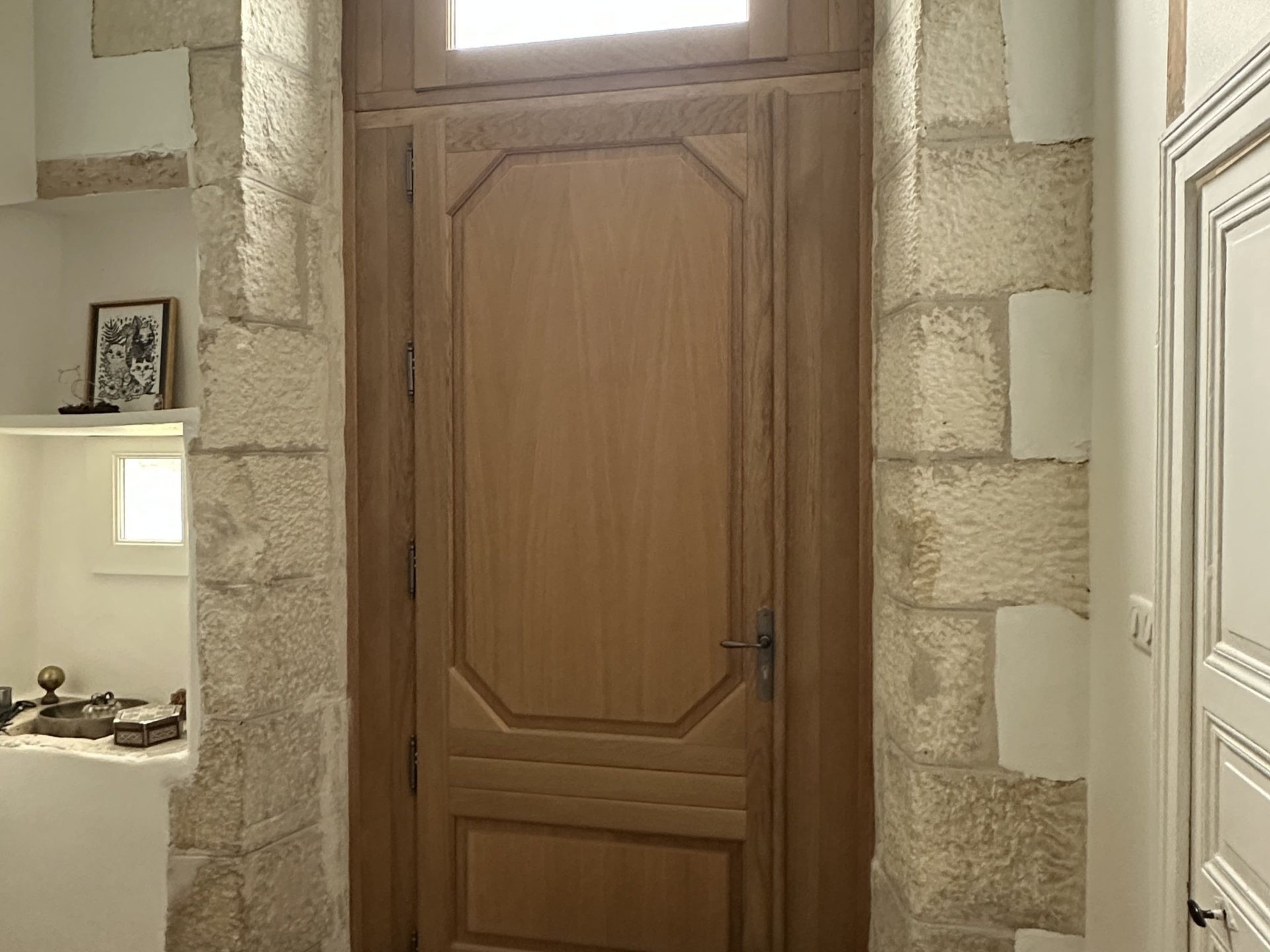 Porte en bois avec fenêtre arquée et carreaux colorés.