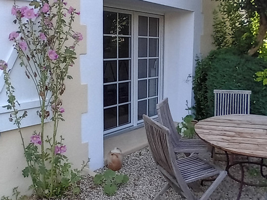 Terrasse avec table, chaises et fleurs.