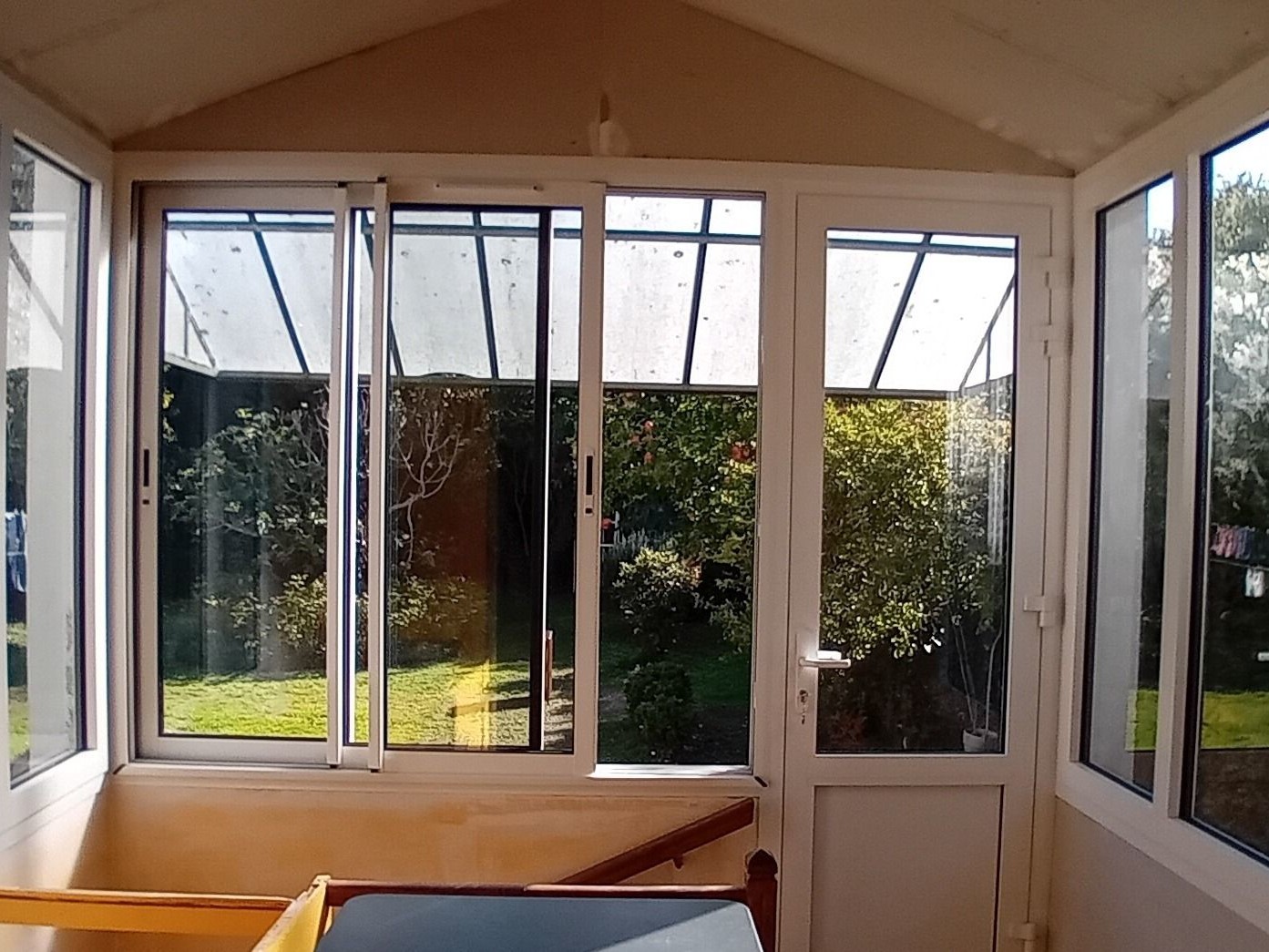 Véranda lumineuse donnant sur le jardin verdoyant.