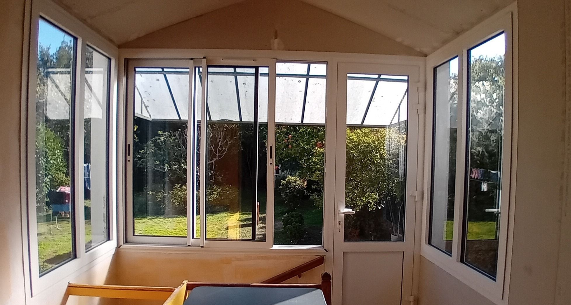 Véranda lumineuse donnant sur le jardin verdoyant.