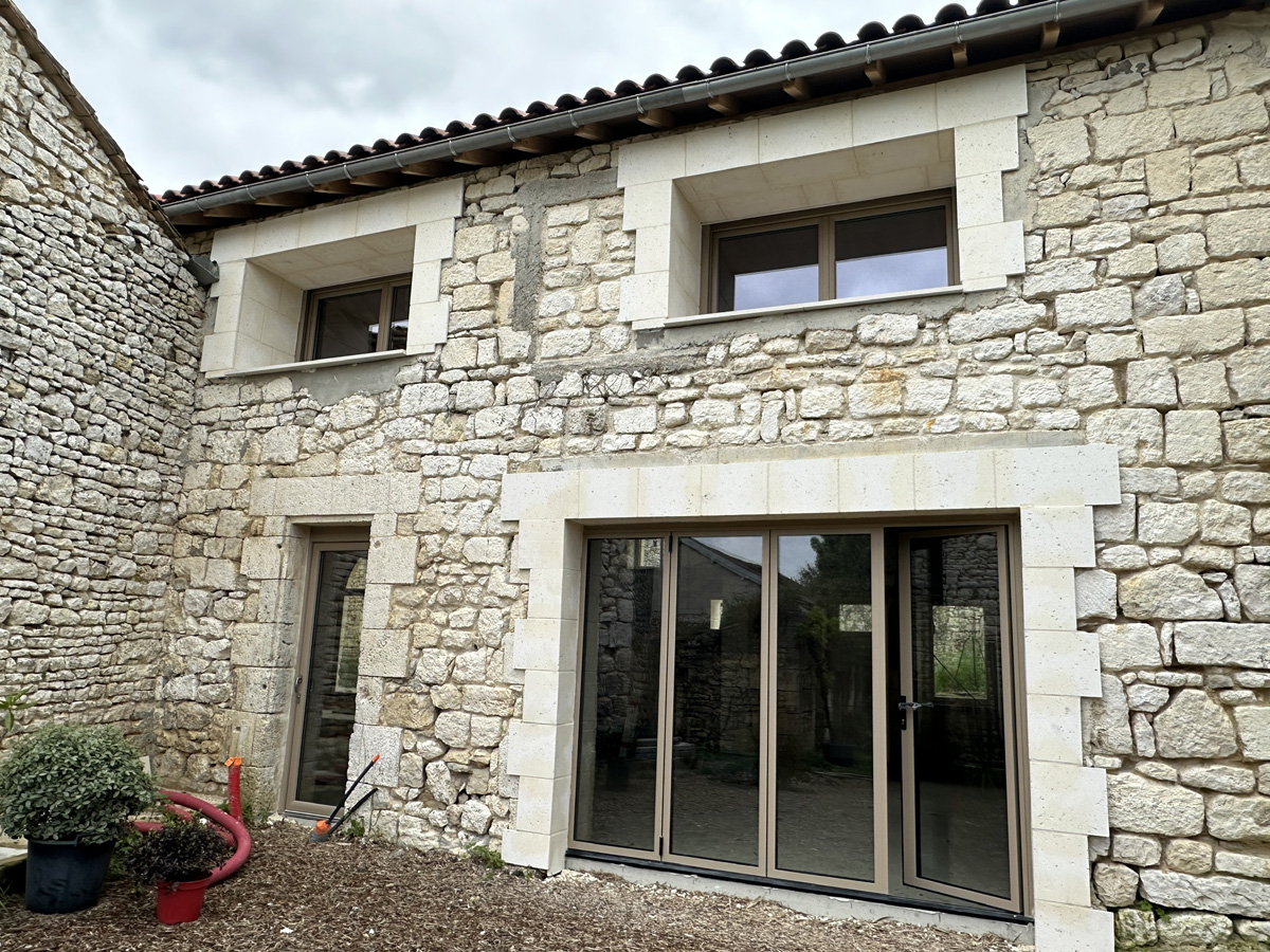 Façade en pierre avec grandes fenêtres modernes.