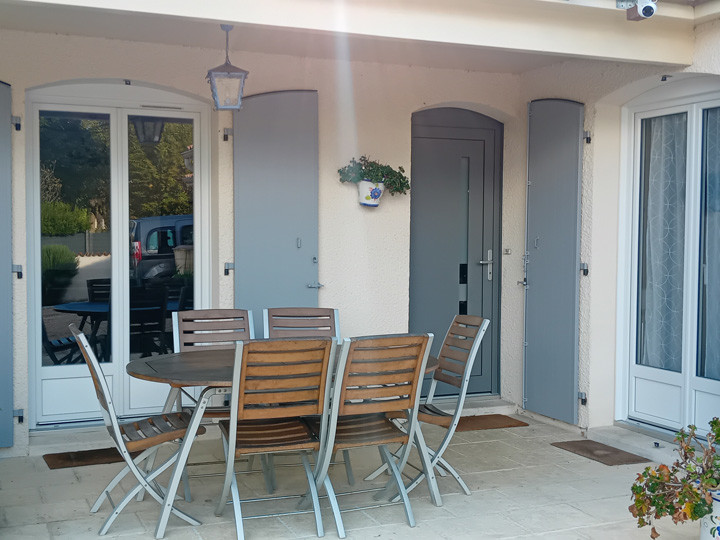 Terrasse couverte avec table, chaises et volets gris